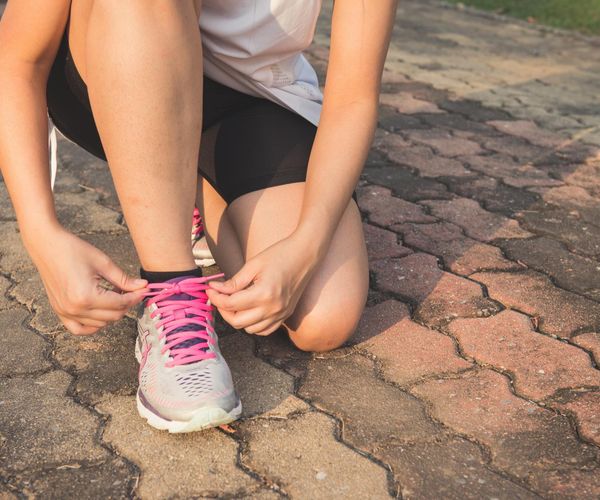 Person tying shoelaces, preparing for a home workout.
